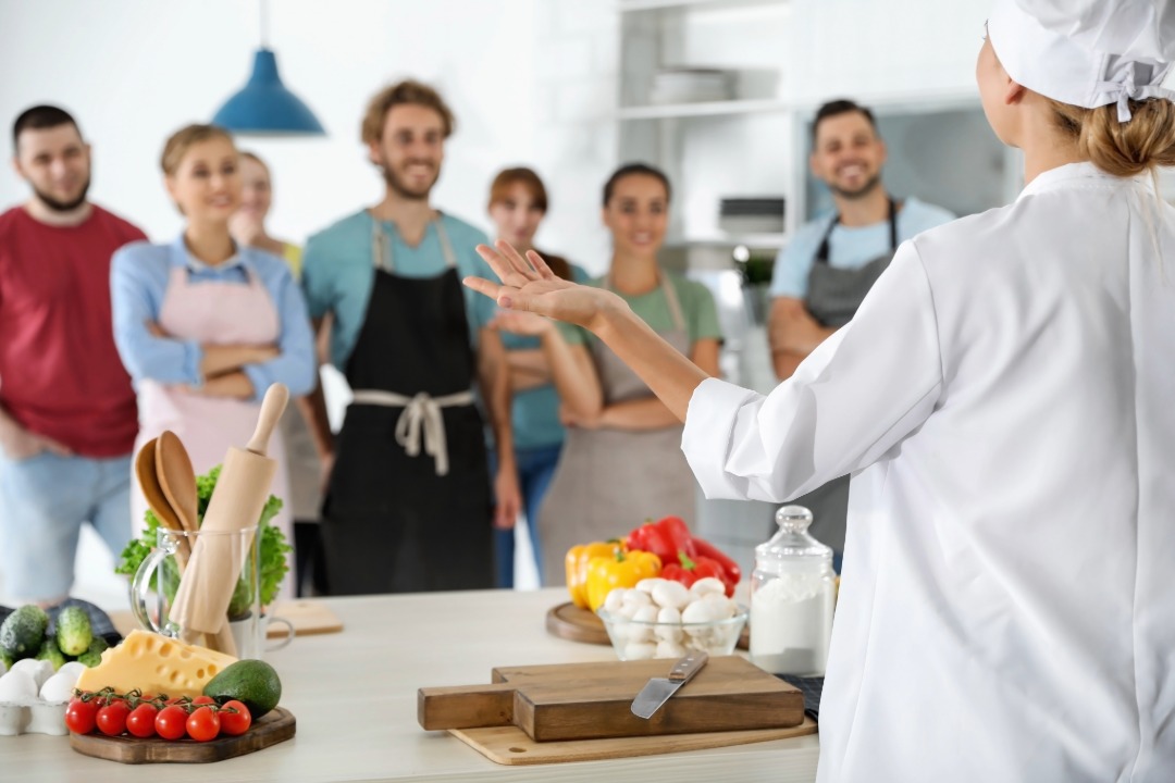 Aula de culinária alemã em grupo, com chef ensinando os participantes